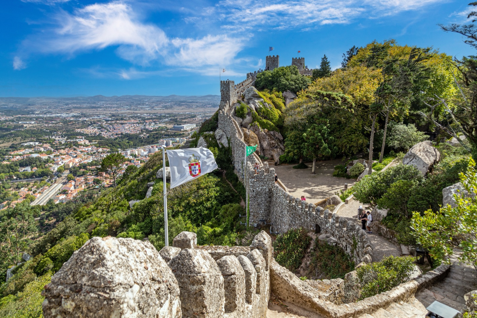 The stone walls and towers of the Moorish Castle running along a wooded ridge, with the town and plains below